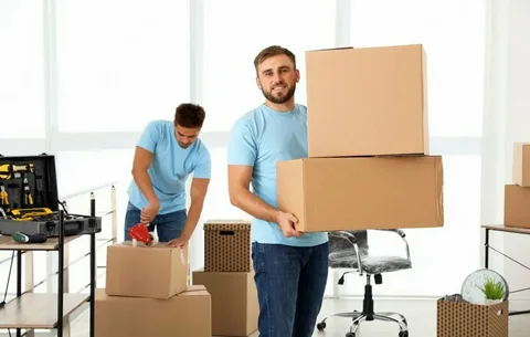 Roommates unpacking home items surrounded by stacked shipping boxes to explain different Types of Moving services