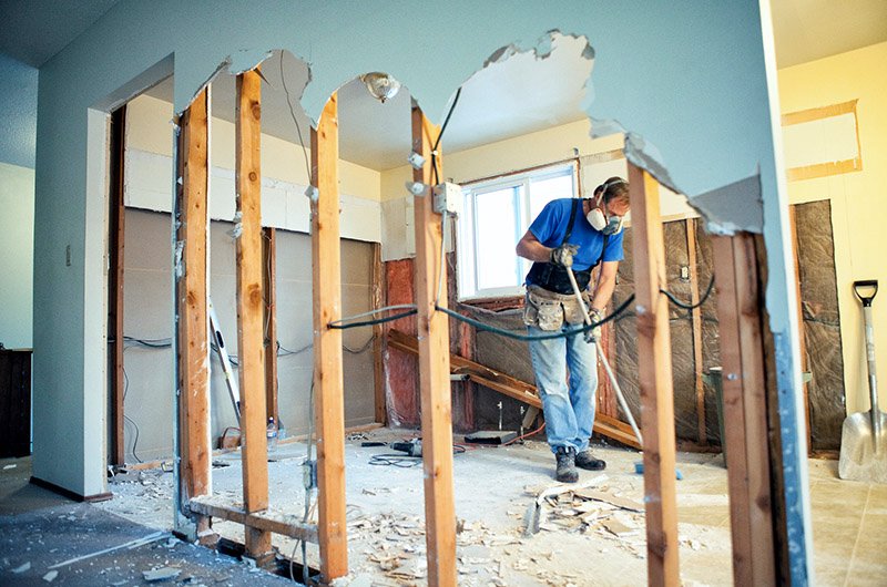 A man is actively working on a basement remodeling project, surrounded by tools and materials.