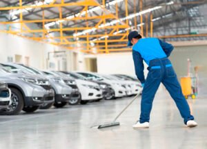 Our Blogs 9 A man cleaning the floor in a car showroom at a dealership, ensuring a tidy and presentable environment for customers.