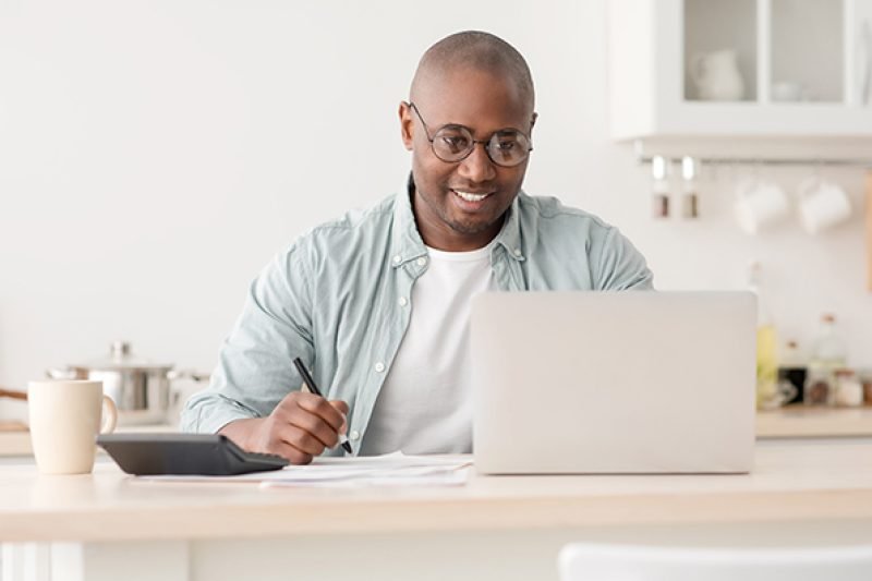 A smiling man working on his laptop, focused on credit repair tasks.