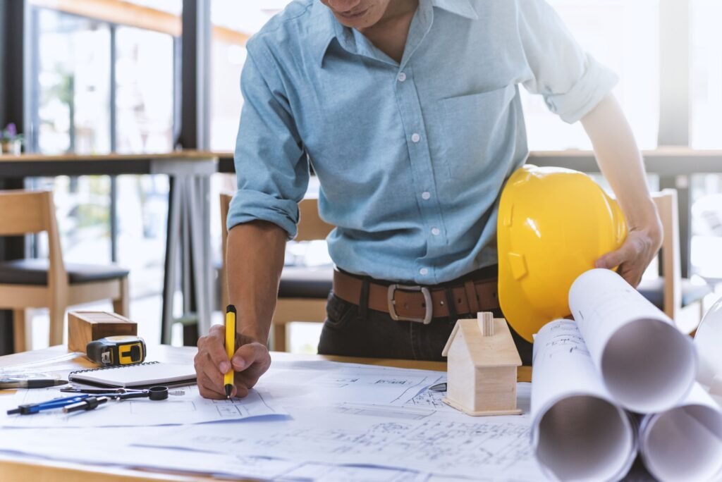 A man in a hard hat and glasses works on a general contracting project, focused on his task.