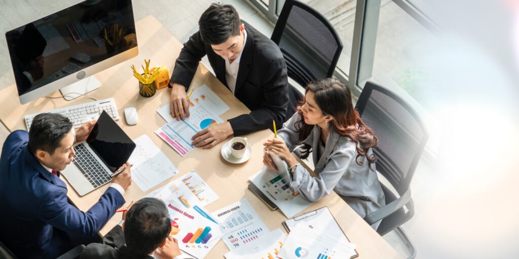 Discover the Best Local Businesses with 100 Local Near 1 A group of business professionals collaborating at a table with laptops and papers, focused on strategies for local businesses.