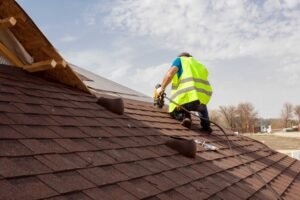 Our Blogs 11 A man in a yellow vest works on a roof, representing local roofing services in action.