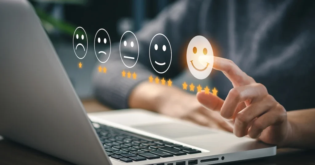 A person selects a glowing five-star smiley face icon from a digital satisfaction scale on a laptop screen.