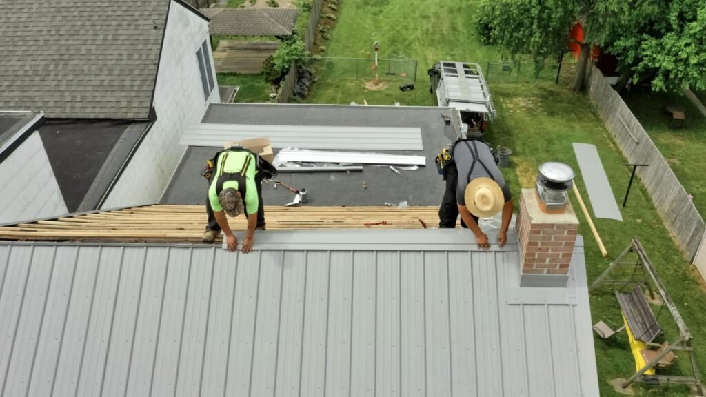 Two men working on roof installation in a backyard, focused on their work amidst tools and materials.