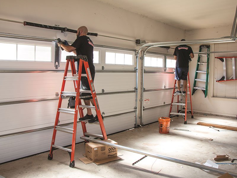 Garage door repair technicians are fixing door from inside