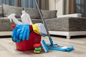 Professional deep cleaning supplies and tools arranged beside a sofa, including microfiber cloths, mop, bucket, and cleaning solutions for thorough residential deep cleaning.
