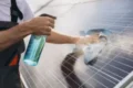 Close-up of a technician using a spray bottle and cloth for professional solar panel cleaning and maintenance.