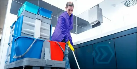 Janitorial worker providing commercial porter services with a mop and wet floor sign