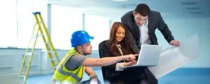 Our Blogs 3 Property managers reviewing facility blueprints on a laptop with a contractor to coordinate professional Property Management Cleaning Services