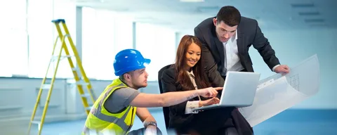 Property managers reviewing facility blueprints on a laptop with a contractor to coordinate professional Property Management Cleaning Services